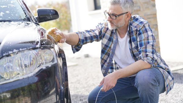 Ein Mann wäscht sein Auto zu Hause, auf seinem Privatgrundstück.