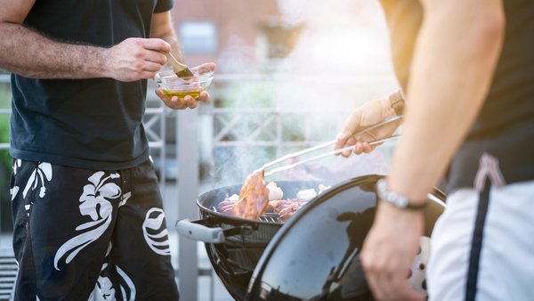 Zwei Personen Grillen auf dem Balkon.