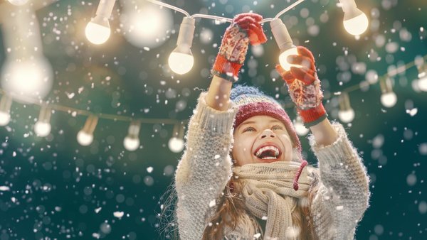 Lachendes Mädchen im Schneegestöber mit Lichterkette